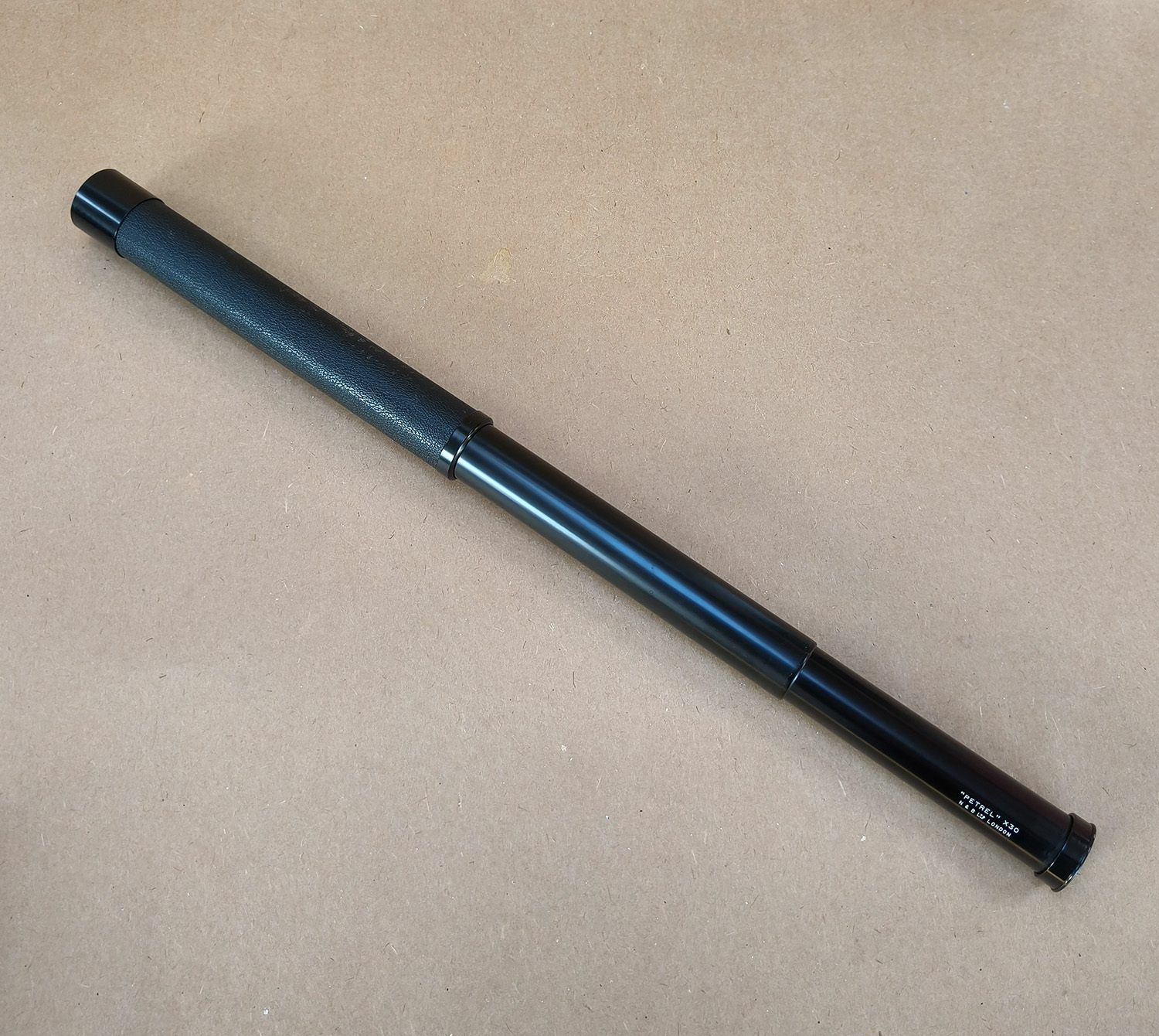For sale is a vintage N & B Ltd London “PETREL” x30 handheld 2-draw telescope, complete with its original brown canvas and leather carry case. This is a classic British-made tubular spyglass with a 30× fixed magnification, designed for field use, birdwatching, nautical spotting, and general outdoor observation. The telescope features a black textured metal body, a smooth draw-tube extension, and quality optics typical of mid-20th-century British craftsmanship.